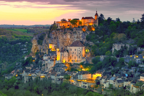 Uitzicht op het verlichte Rocamadour bij zonsondergang, gezien vanaf Flower Camping Les Ondines in Occitanië.