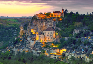Udsigt over den oplyste middelalderby Rocamadour ved solnedgang, set fra Flower Camping Les Ondines i Occitanie.