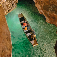 A boat glides on crystal-clear water inside a scenic cave near Souillac in the Occitanie region of France.
