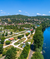 Aerial view of the Souillac surroundings in Occitanie, France, featuring a river, town, and lush hills.