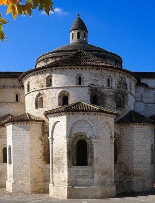 Historic church with round dome in Souillac, Occitanie, France, under a clear blue sky and autumn leaves.