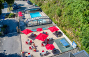 Vista aérea de Flower Camping La Plage en Nouvelle-Aquitaine, Francia con piscina, sombrillas rojas y tumbonas.