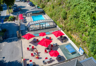 Luchtfoto van Flower Camping La Plage in Nouvelle-Aquitaine, Frankrijk met zwembad, rode parasols en ligstoelen.