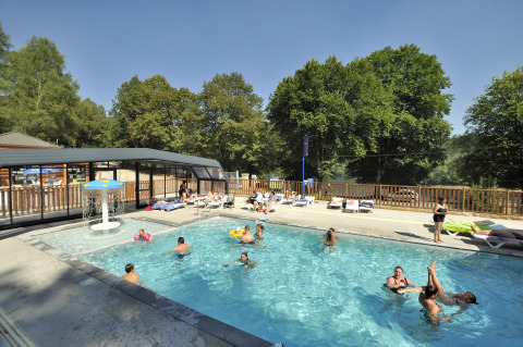 Piscine extérieure animée au Flower Camping La Plage avec vacanciers et transats en Nouvelle-Aquitaine, France.