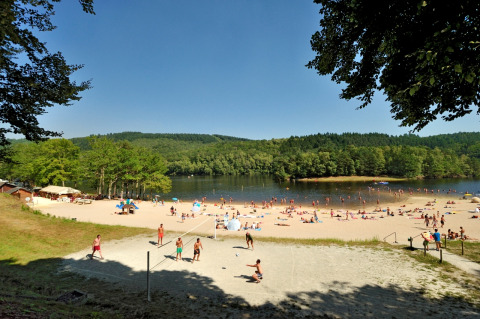 People relax and play at the sandy lakeside beach of Flower Camping La Plage in Nouvelle-Aquitaine, France.