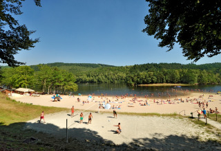 Folk nyder en solrig dag på sandstranden ved søen på Flower Camping La Plage, Nouvelle-Aquitaine.
