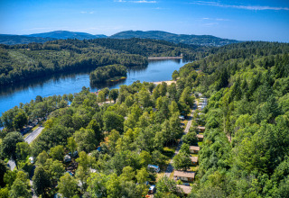 Vista aérea del parque vacacional Flower Camping La Plage en Nouvelle-Aquitaine, Francia, rodeado de bosque y lago.