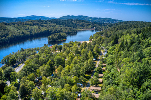 Vue aérienne du camping Flower La Plage en Nouvelle-Aquitaine, France, entouré de forêt et d’un lac paisible.