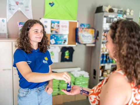 Receptioniste geeft een sleutel aan een gast bij Flower Camping La Plage in Nouvelle-Aquitaine, Frankrijk.