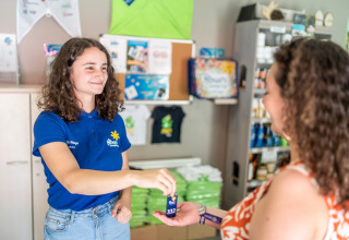 Receptionist consegna una chiave a un ospite al Flower Camping La Plage in Nouvelle-Aquitaine, Francia.