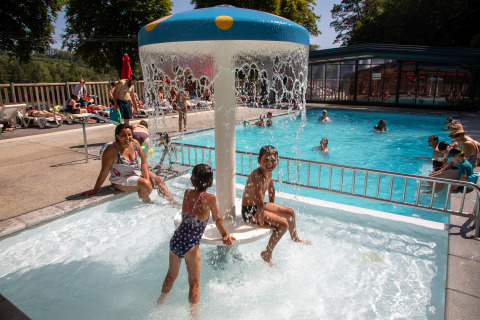 Niños juegan bajo un hongo de agua en la piscina de Flower Camping La Plage, Nueva Aquitania, Francia.