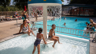 Børn leger under vandsvamp i poolområde på Flower Camping La Plage, Nouvelle-Aquitaine, Frankrig.