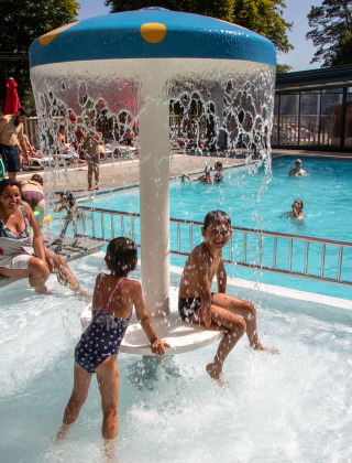 Børn leger under vandsvamp i poolområde på Flower Camping La Plage, Nouvelle-Aquitaine, Frankrig.