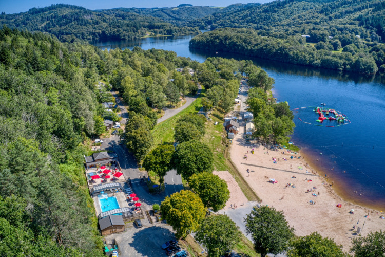 Aerial view of Flower Camping La Plage in Nouvelle-Aquitaine, France, with beach, lake, pool, and trees.