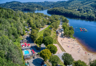 Aerial view of Flower Camping La Plage in Nouvelle-Aquitaine, France, with beach, lake, pool, and trees.