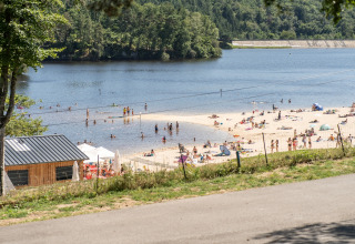 Strand og badende gæster ved Flower Camping La Plage i Nouvelle-Aquitaine, Frankrig, omgivet af skov.