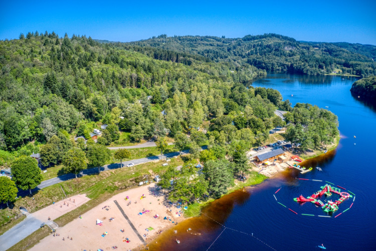 Vista aerea di Flower Camping La Plage in Nouvelle-Aquitaine con spiaggia, lago, foresta e parco acquatico.