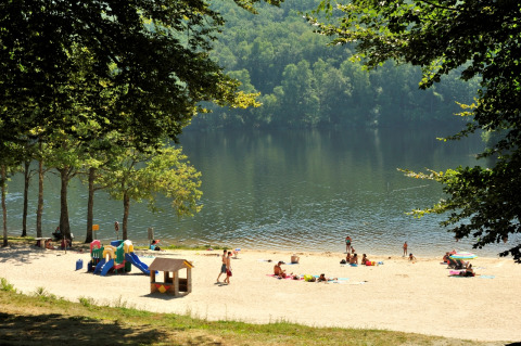 Badestrand med legeplads ved søen, omgivet af træer, på Flower Camping La Plage i Nouvelle-Aquitaine.