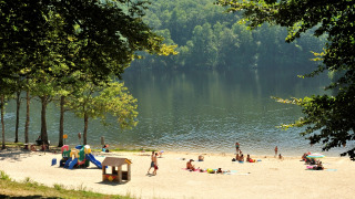 Badestrand med legeplads ved søen, omgivet af træer, på Flower Camping La Plage i Nouvelle-Aquitaine.