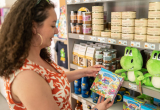 Mujer observa juego Camping Party en tienda de recuerdos de Flower Camping La Plage en Nouvelle-Aquitaine, Francia.