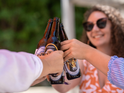 Menschen stoßen mit Bierflaschen an und genießen die Sonne bei Flower Camping La Plage in Nouvelle-Aquitaine, Frankreich.
