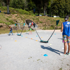 Børn og voksne spiller badminton udendørs ved Flower Camping La Plage, Nouvelle-Aquitaine, Frankrig.