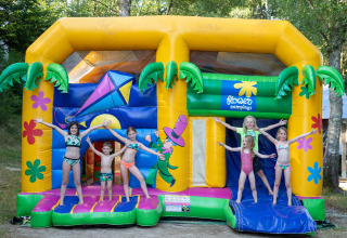 Børn leger i badetøj på en farverig hoppeborg ved Flower Camping La Plage i Nouvelle-Aquitaine, Frankrig.