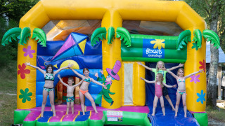 Børn leger i badetøj på en farverig hoppeborg ved Flower Camping La Plage i Nouvelle-Aquitaine, Frankrig.