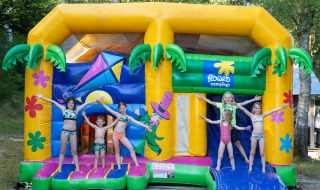 Børn leger i badetøj på en farverig hoppeborg ved Flower Camping La Plage i Nouvelle-Aquitaine, Frankrig.