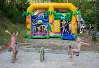 Kinder spielen auf einer Wippe und einer Hüpfburg im Flower Camping La Plage, Nouvelle-Aquitaine, Frankreich.
