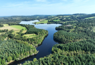 Aerial view of a scenic lake surrounded by forests and green fields at Flower Camping La Plage, France.