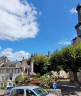 Billede af det charmerende centrum af Treignac-sur-Vézère med historiske bygninger og en kirke.