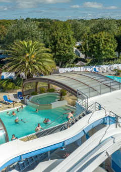 Parc de vacances en Bretagne, France, avec piscine couverte, toboggans aquatiques et vacanciers détendus.