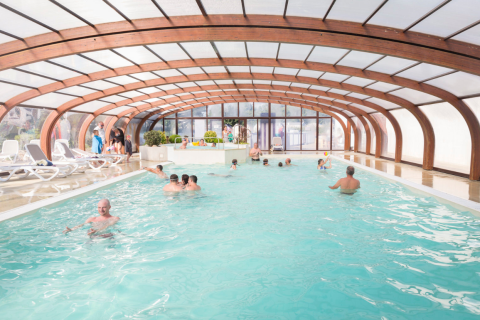 Überdachtes Schwimmbad mit Gästen im Flower Camping Cap Finistère, Bretagne, Frankreich.