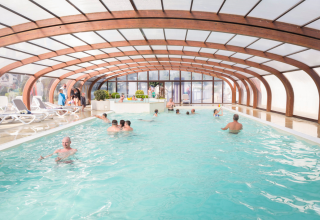 Overdækket swimmingpool med ferieparkens gæster, Flower Camping Cap Finistère, Bretagne, Frankrig.