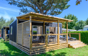 Moderne hytte med overdækket terrasse og liggestole i Flower Camping Cap Finistère, feriepark i Bretagne, Frankrig.