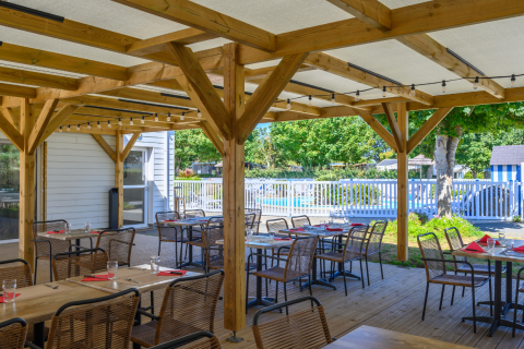 Überdachter Außenbereich eines Restaurants mit Blick auf den Pool im Flower Camping Cap Finistère, Bretagne.
