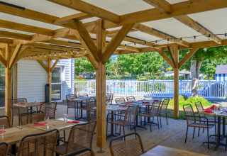 Überdachter Außenbereich eines Restaurants mit Blick auf den Pool im Flower Camping Cap Finistère, Bretagne.