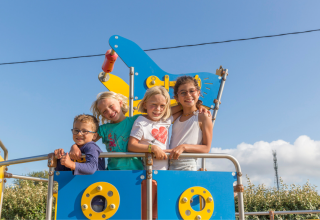 Cuatro niños sonrientes posan juntos en un parque infantil en Flower Camping Cap Finistère, Bretaña, Francia.