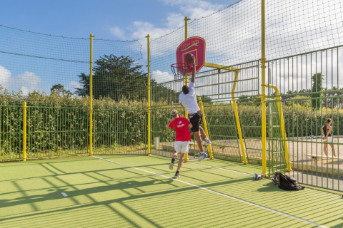 Twee mensen spelen basketbal op een buitenveld bij Flower Camping Cap Finistère in Bretagne, Frankrijk.