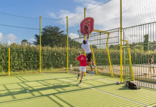 Twee mensen spelen basketbal op een buitenveld bij Flower Camping Cap Finistère in Bretagne, Frankrijk.