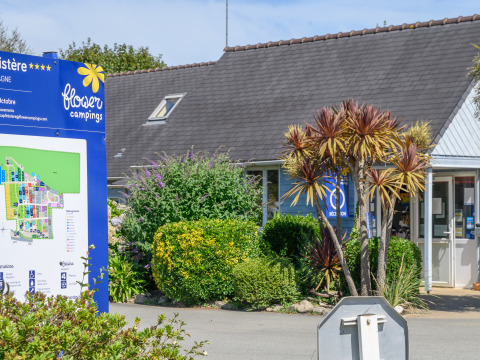 Toegang tot Flower Camping Cap Finistère vakantiepark in Bretagne, Frankrijk met blauw bord en receptie.