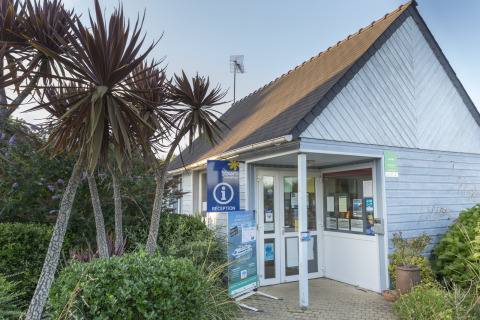 Receptiegebouw van Flower Camping Cap Finistère in Bretagne, Frankrijk, met palmbomen en groene planten.