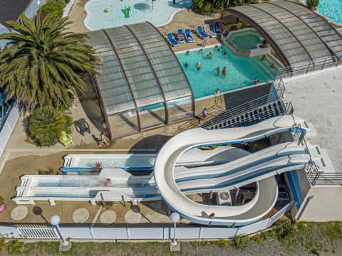 Feriepark i Bretagne, Frankrig med overdækket pool, rutsjebaner og glade gæster ved Flower Camping Cap Finistère.