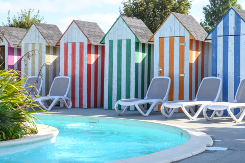 Gekleurde strandhokjes en ligstoelen bij het zwembad op Flower Camping Cap Finistère in Bretagne, Frankrijk.