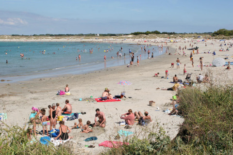 Drukke strand bij Flower Camping Cap Finistère in Bretagne, Frankrijk, met mensen die zwemmen en zonnen.