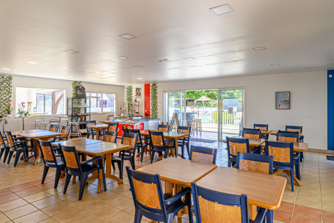 Sala da pranzo con tavoli in legno al Flower Camping Cap Finistère, villaggio vacanze in Bretagna, Francia.