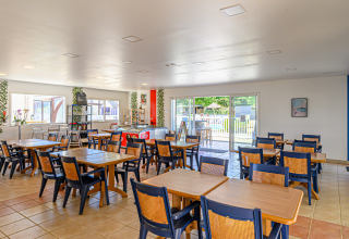 Dining room with wooden tables and chairs at Flower Camping Cap Finistère holiday park in Brittany, France.