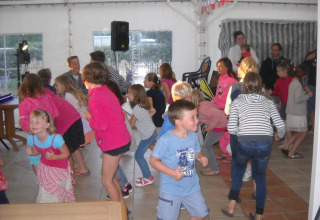 Kinder tanzen und spielen drinnen im Flower Camping Cap Finistère, einem Ferienpark in der Bretagne, Frankreich.