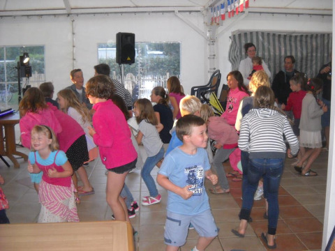 Niños bailando y jugando en el interior de Flower Camping Cap Finistère, un parque de vacaciones en Bretaña, Francia.